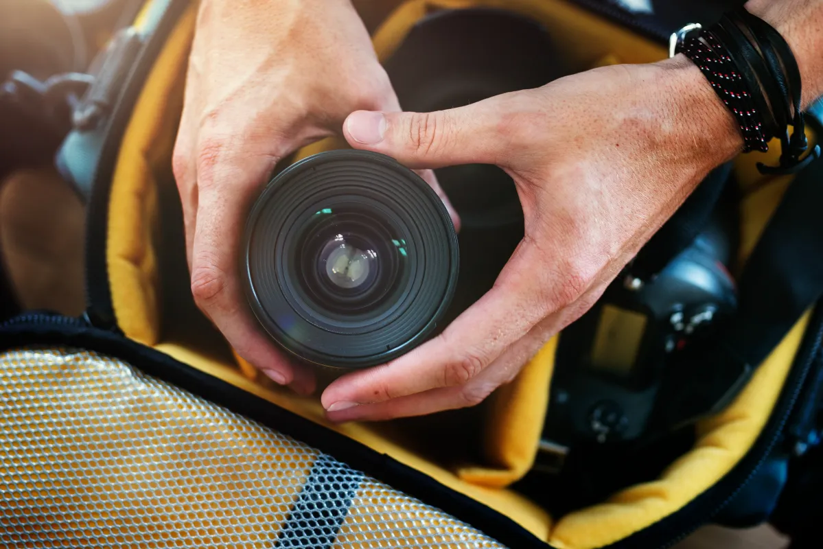 closeup of hands getting camera lens from bag